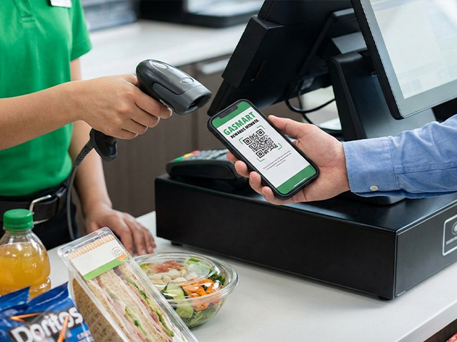 Video of a C-store clerk scanning a QR code on a customer's phone at checkout.